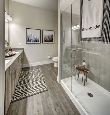 A bathroom with a glass shower stall and a towel hanging on the glass door at Arise Riverside Apartments, Austin, TX, 78741